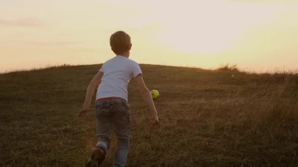 Futbol topunun peşinden koşan çocuk. Açık hava eğlencesi. Gökyüzü ve Ufuk. — Stok video