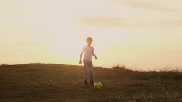 Futbol topunun peşinden koşan çocuk. Açık hava eğlencesi. Gökyüzü ve Ufuk. — Stok video