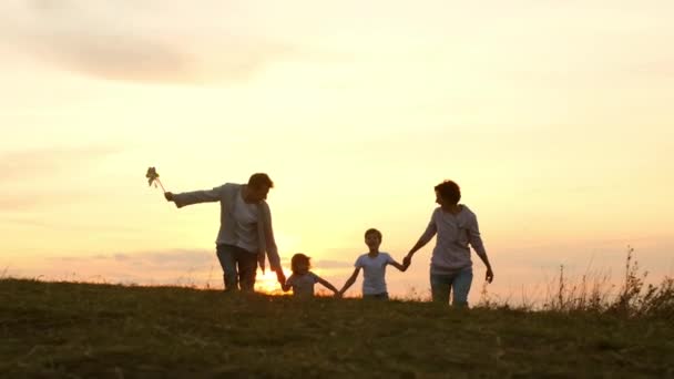 Férias em família na natureza. Jovem mãe, pai e suas filhas e filho se encontram ao pôr do sol. — Vídeo de Stock