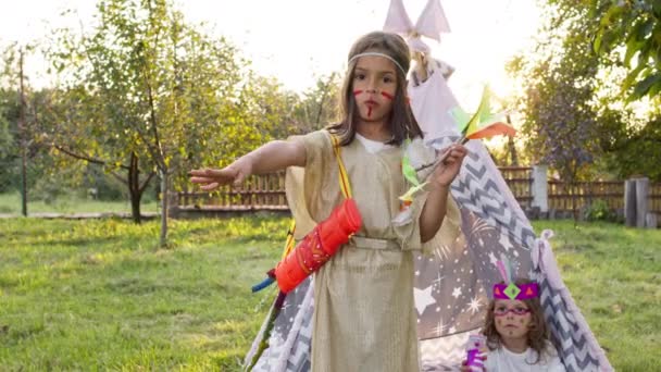 Vacaciones para niños. Dos chicas guapas con disfraces de indios en el jardín. — Vídeos de Stock