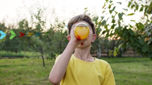 子供の休日。ジュースのボトルから男の子の飲み物。顔に描かれている。インド人の姿をしている。. — ストック動画