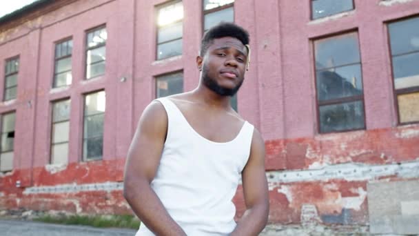 Mladý černoch stojící na ulici. Za ním jsou staré domy. — Stock video