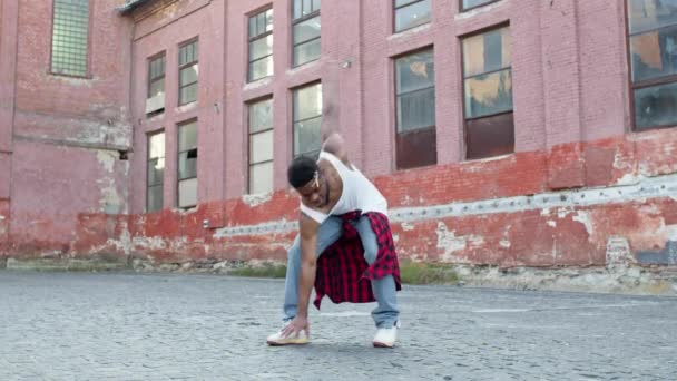Junger Schwarzer tanzt auf der Straße. Er hat stylische Frisur und Kleider, die an der Taille gebunden sind. — Stockvideo