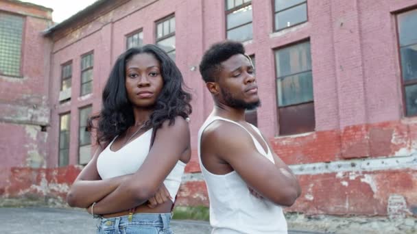 Young Couple On The Street. Black Guy And Girl Stand Back To Back With Their Hands Folded On Their Chests. Young Couple With Serious Facial Expression. — Stock Video