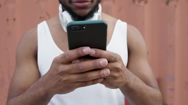 O jovem negro com telemóvel. Ele segura o telefone nas mãos e usa-o apenas os lábios e o queixo são visíveis. — Vídeo de Stock