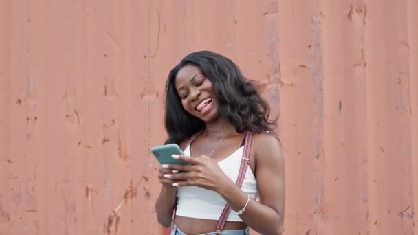 Menina bonita alegre. Menina preta nova com telefone celular em suas mãos. — Vídeo de Stock