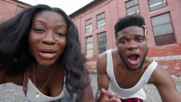 Straatdansen. Een jong stel dat op straat danst. Zwarte man en meisje bewegen ritmisch. Ze maken dezelfde bewegingen en lachen. Hun gezichten dicht bij de camera. — Stockvideo