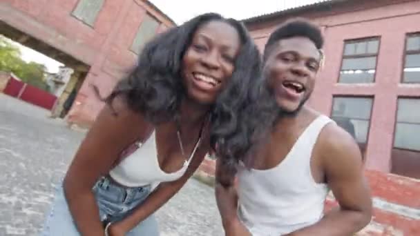 Χορός δρόμου. Νεαρό ζευγάρι που χορεύει στο δρόμο. Μαύρος και κορίτσι κινούνται ρυθμικά. Κάνουν κινήσεις και χαμογελούν. Τα πρόσωπά τους κοντά στην κάμερα. — Αρχείο Βίντεο