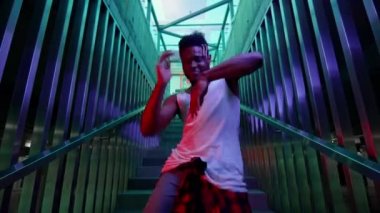 Genç siyahi adam merdivenlerde dans ediyor. Işık Mavi ve Yeşil Renkler Oluşturur.