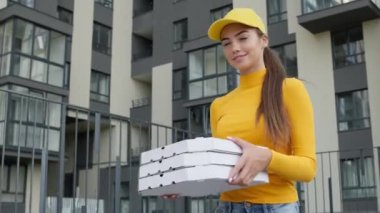 Genç Kız Pizza Teslimatçısı Ellerinde Kutularla Sokakta Yürüyor. Sarı Şapkalı ve Süveterli Güzel Esmer.