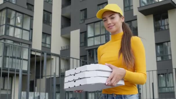 Молода дівчина Піца Доставка Працівник ходити з коробками в руках на вулиці. Гарненька брюнетка в жовтий капелюх і светр . — стокове відео