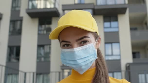 Bella bruna in cappello giallo e maglione. Ragazza in maschera medica per proteggere contro l'infezione virale. — Video Stock