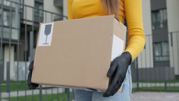 Manos de niña caja de transporte. Ella está usando guantes. Trabajador de parto. Cara invisible. Ella va y lleva la caja en la calle. — Vídeo de stock