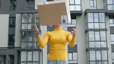 Genç kız teslimat işçisi elinde kutuyla sokakta dikiliyor. Kutuyu fırlatıyor ve yakalıyor..