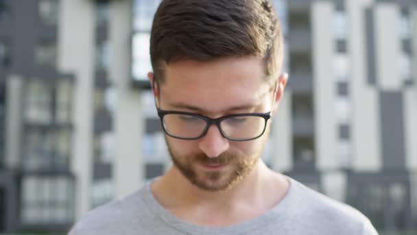 Portrét mladého muže s bradkou v brýlích. Za ním Multi Florey Building. — Stock video