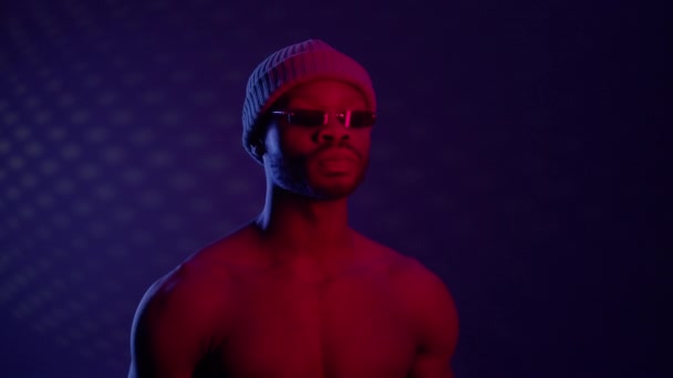 Noir guy dans sombre chambre avec lunettes de soleil et chapeau. — Video