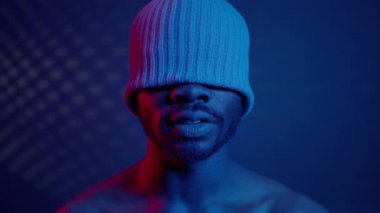 Mavi ışıklandırmalı siyah adam. Gözlerini kapatan şapkasının üzerinde..