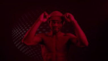 Kırmızı ışıklandırmalı siyah adam. Gözlerini kapatan şapkasının üzerinde..