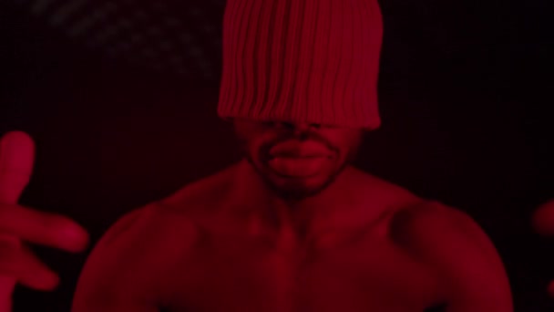 Ragazzo nero in camera con illuminazione rossa. Sul suo berretto che chiude gli occhi. — Video Stock
