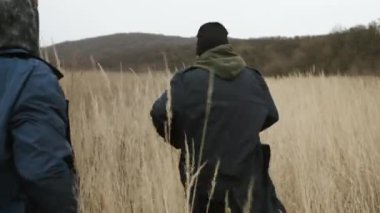 Tarlada koşan iki arkadaş. Arkadan Görüntüle.