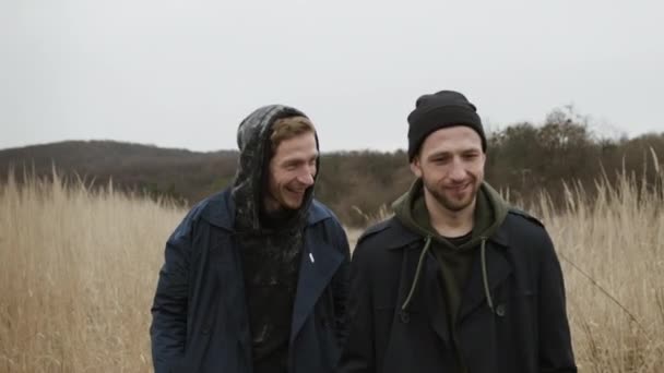 Twee jonge kerels die over de weg lopen in de natuur. Ze lachen en lachen.. — Stockvideo