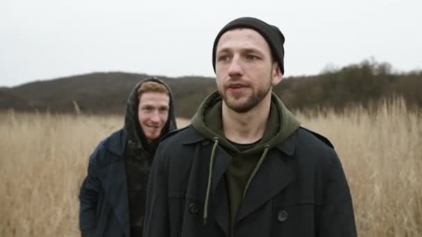 Twee vrienden wandelen op de weg in het veld. — Stockvideo