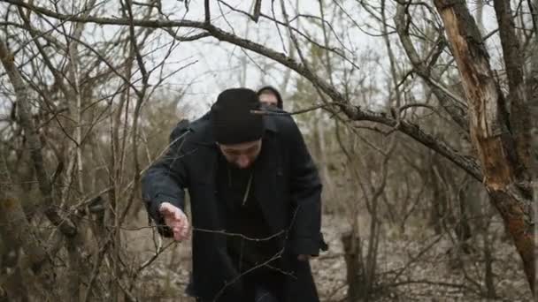 To unge fyre går langs stien mellem tørre træer. Gå i naturen af to stilfulde venner. – Stock-video