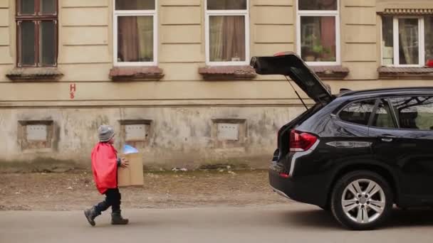 Little Boy And His Parents Put Boxes In The Car Trunk With Things — Stock Video