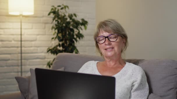 Glimlachend Blondje met bril in de kamer met mooi interieur. Ze lacht en praat vrolijk.. — Stockvideo