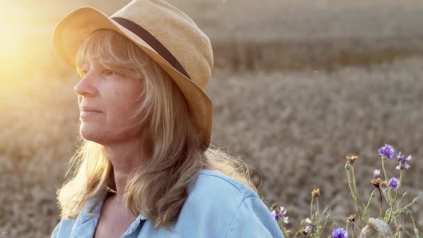 Romantic Image Of Middle Aged Woman On The Field. Woman In Hat Stands And Looks At The Sunrise. — Stock Video