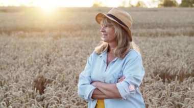 Buğday tarlasında sarışın. Elleri göğsünde ve gülümseyen bir kadın. Eşsiz Gündoğumu. Uzun Saçlı Güzel Sarışın.