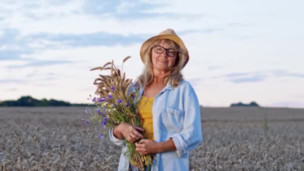 하늘의 배경에서 부 케와 함께 한 여인의 낭만적 인 이미지. 그녀는 물방아를 이용 한 밀 밭의 중간에서 꽃을 손으로 들고 있다. — 비디오