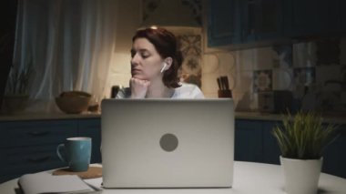 Mutfakta dizüstü bilgisayarlı bir kadın. Bir şey onu şaşırtıyor ve gülümsüyor..