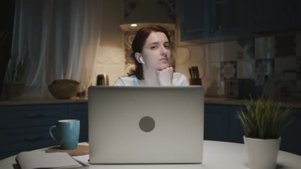 Mulher na cozinha com laptop. Algo a surpreende e ela sorri. — Vídeo de Stock