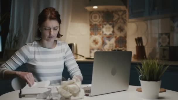 Mutfakta dizüstü bilgisayarlı bir kadın. Defterindeki yaprakları koparıp atıyor.. — Stok video