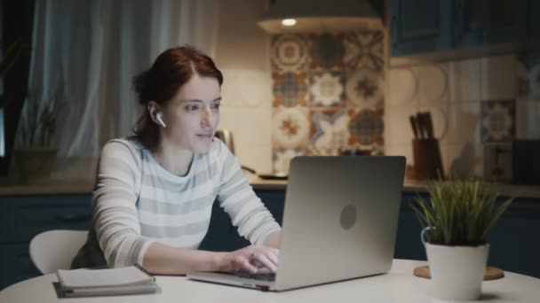 Žena v kuchyni s laptopem. Něco ji překvapí a ona se usměje. — Stock video