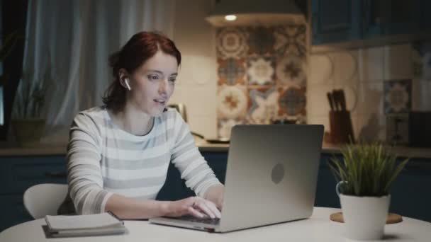 Mulher na cozinha com laptop. Algo a surpreende e ela sorri. — Vídeo de Stock