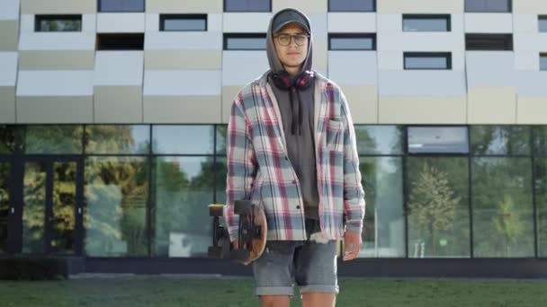 Guy läuft mit Skateboard die Straße hinunter. Kerl in Shorts und Jacke. — Stockvideo