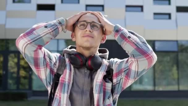 Portrait de jeune homme dans la rue. Guy prend ses mains derrière sa tête comme si très surpris ou fatigué. — Video