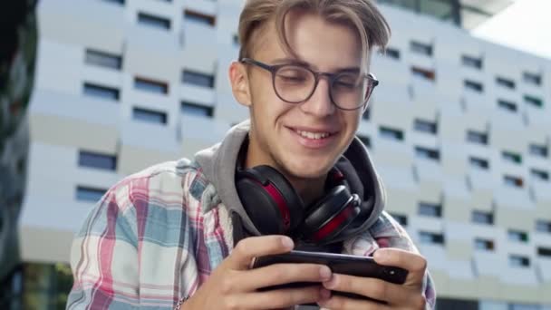 젊은 남자가 거리에서 폰을 들고 있다. 안경을 쓴 귀여운 금발의 남자 (Cute Blond Guy With Glasses) 는 폰을 사용 한다. 그는 맹세 한다. — 비디오