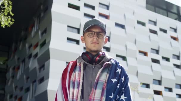 Retrato de um jovem na rua. Ele tem a bandeira dos EUA nas costas. — Vídeo de Stock