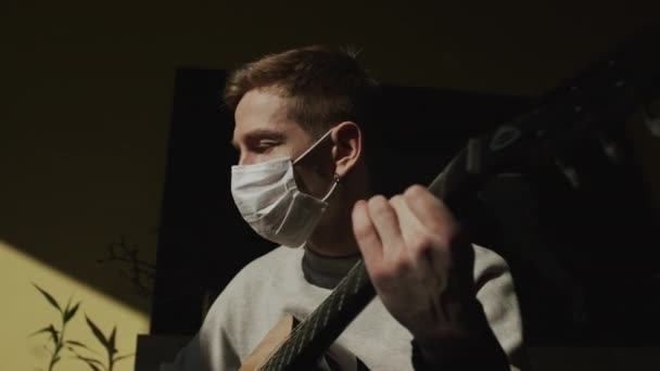 Chlápek v masce. Smutný pohled. Mladý muž hraje na kytaru. — Stock video