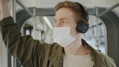 Genç adam yüzünde tıbbi maskeyle otobüse biniyor. Salgında Sağlığın Korunması.