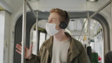 Genç adam yüzünde tıbbi maskeyle otobüse biniyor. Salgında Sağlığın Korunması.