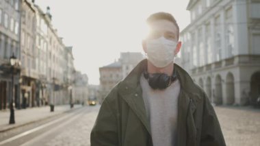 Caddede yürüyen tıbbi maskeli genç adam. Salgın yüzünden sokaklar garanti altında. Adam kulaklık takıyor..
