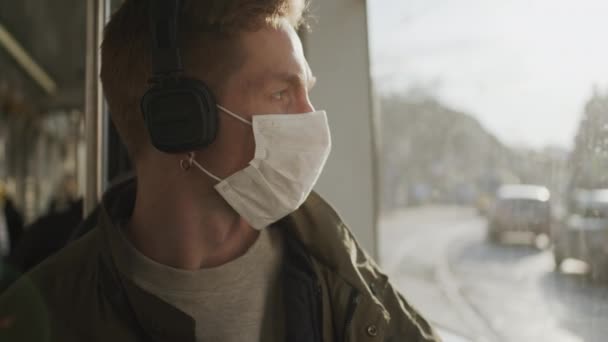 小伙子坐在公共汽车上，脸上戴着医疗面具。在流行病中保护健康. — 图库视频影像