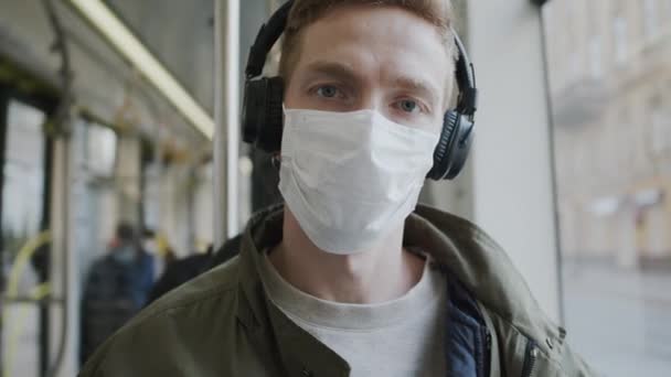 小伙子坐在公共汽车上，脸上戴着医疗面具。在流行病中保护健康. — 图库视频影像
