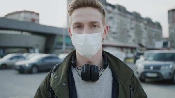 Fiatal fickó orvosi maszkkal az arcán. Egészségvédelem egy járványban. Egy fickó áll az utcán.. — Stock videók