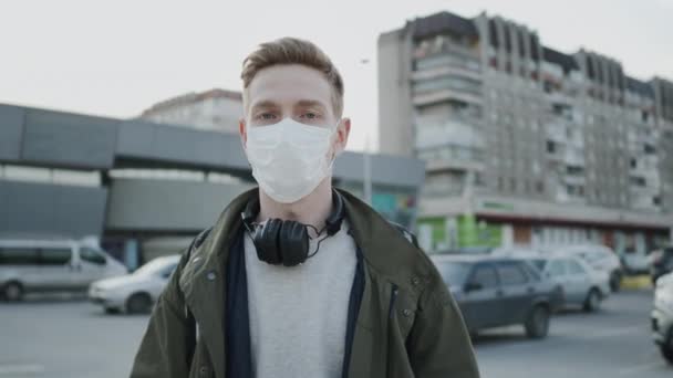 Ung kille med medicinsk mask på ansiktet. Skydda hälsan i en epidemi. Killen som står på gatan. — Stockvideo