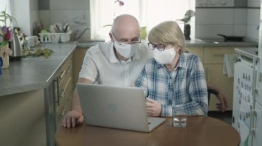 Maskeli adam ve kadın laptopta oturuyor..